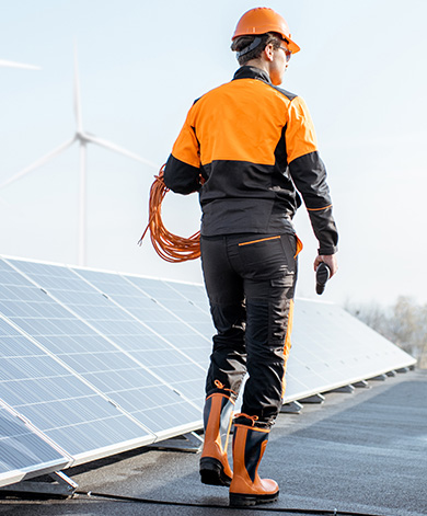 A sustainable energy technician walking past solar panels